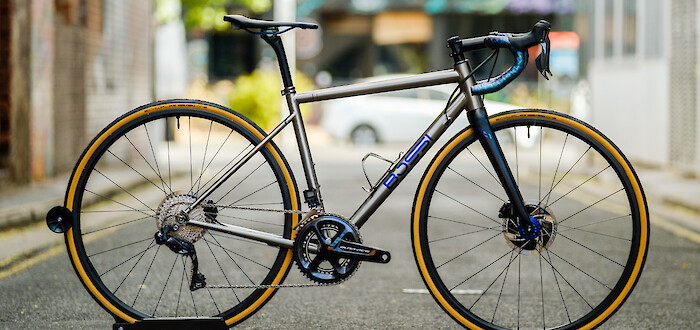A Bossi Summit titanium bicycle with custom-painted blue highlights, shot in a city alleyway