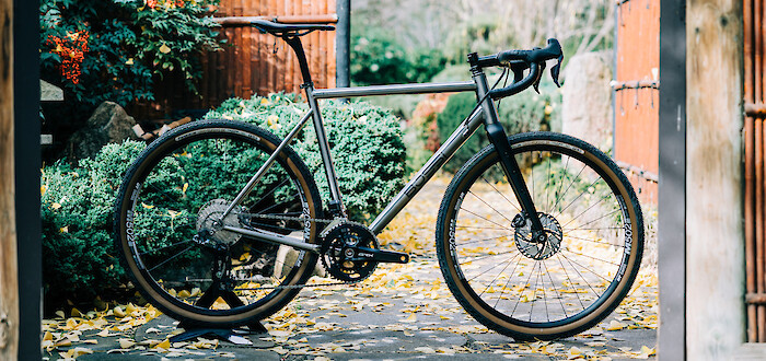 Bossi Grit SX titanium bicycle in a custom build, viewed against a leafy Japanese garden