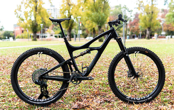Custom-built Ibis Mojo 3 carbon mountain bike, in a leafy autumn-tinged park