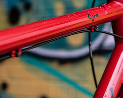 Detail of a Surly Ogre frame against a graffitied wall, rain droplets on the top tube