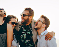 A group of friends, back-lit on a sunny day, laughing at something apparently hilarious.